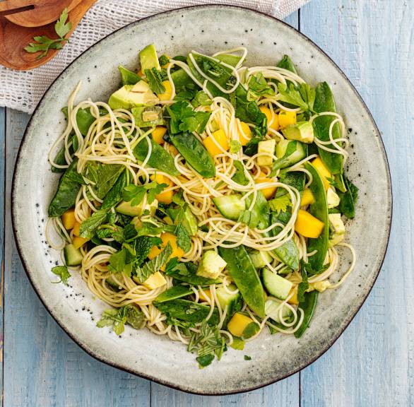 Veganer Nudelsalat aus Capellini mit Avocado, Mango und Gurke angerichtet auf einem großen Teller