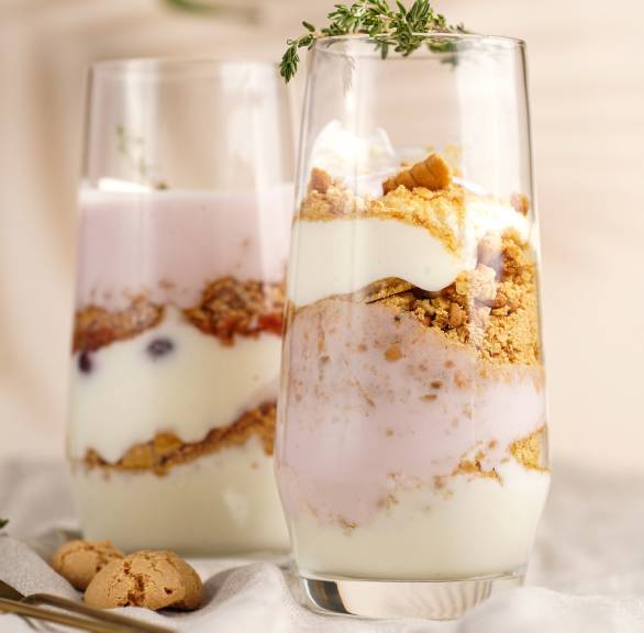 Zwei Gläser mit Amarettini-Dessert mit Beeren und Joghurt auf einem Tisch