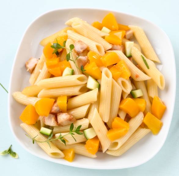 Nudelsalat mit Penne, Gurke und gebratenen Hähnchenbrustfiletstücken angerichtet auf einem tiefen Teller