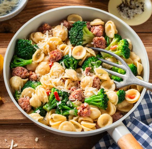 Pfanne mit Orecchiette, Salsiccia und Brokkoli auf einem Holztisch