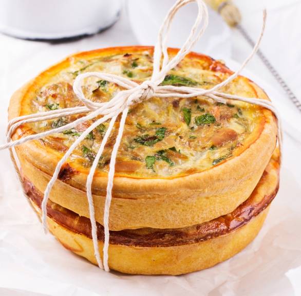 Selbstgebackene Thunfisch-Quiche angerichtet mit Schnur auf einem weiß gedeckten Tisch