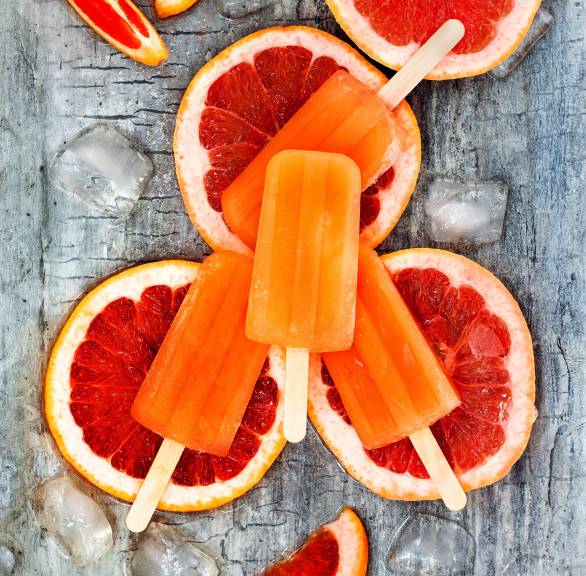 Selbstgemachtes Aperol-Stieleis angerichtet auf Grapefruitscheiben von oben auf einem Tisch