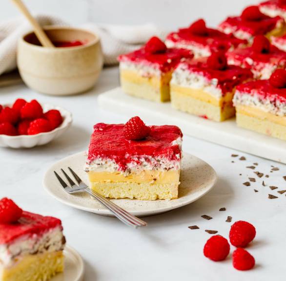 Ein Stück Himbeer-Stracciatella-Blechkuchen mit Pudding auf einem Kuchentelle
