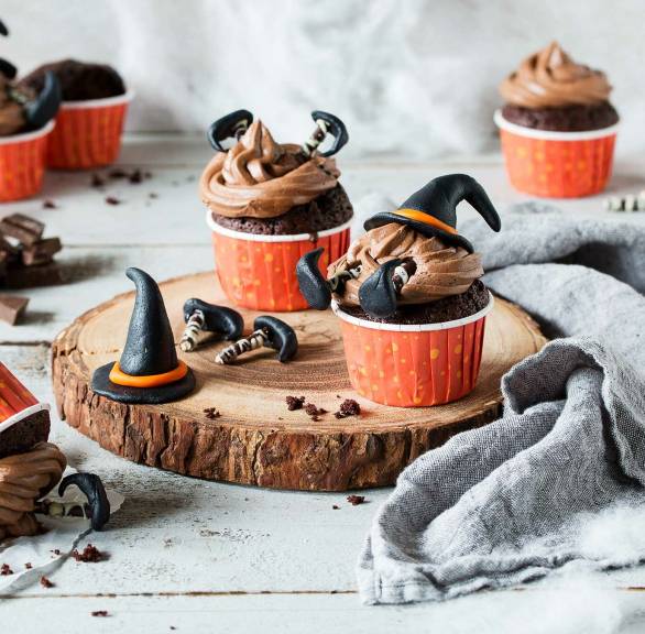 Selbstgebackene Hexen-Cupcakes auf einem für Halloween dekorierten Tisch