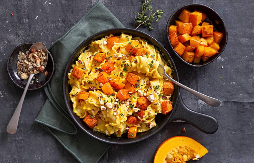 Mafaldine Bandnudeln in einer Pfanne mit Kürbiswürfeln getoppt