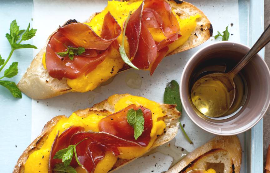 Crostini mit Kürbis und Bresaola belegt auf einem eckigen Teller