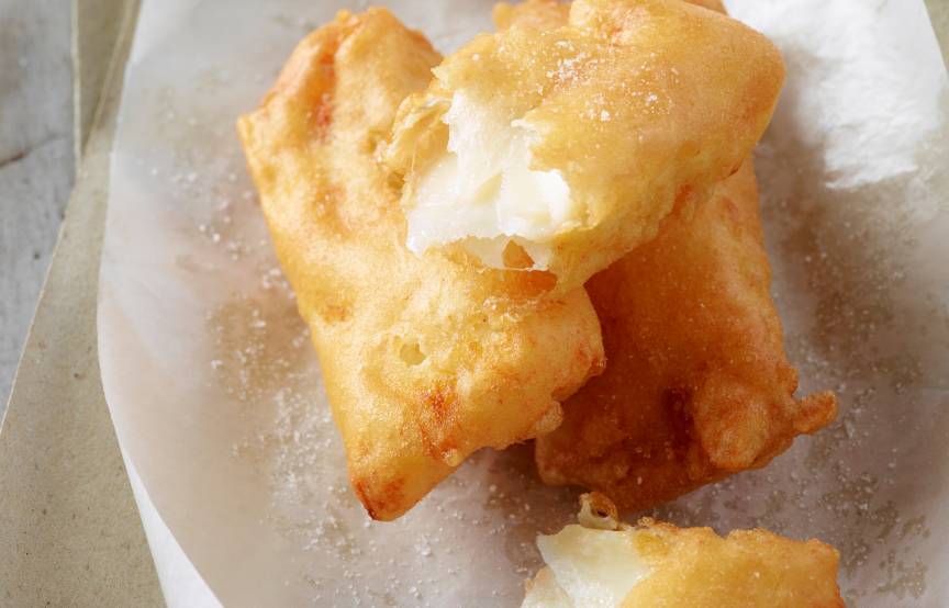 Stücke frittierten Stockfischs auf einem Teller, daneben ein Schälchen Salz