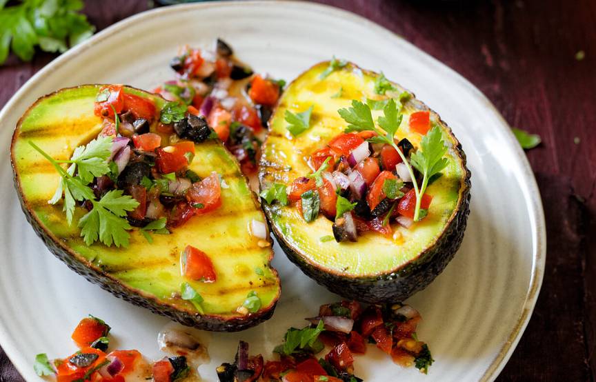 Zwei Gegrillte Avocadohälften mit Tomatensalsa getoppt auf einem Teller