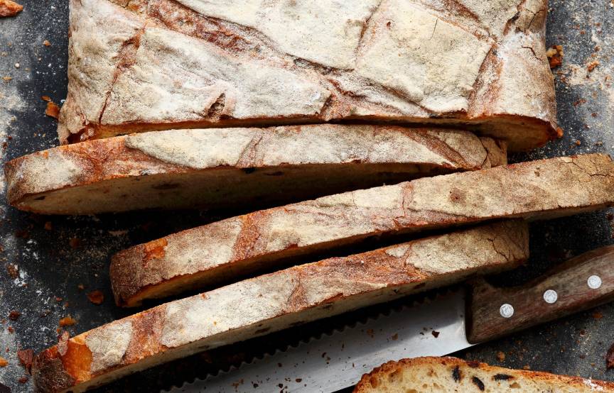 Brotlaib angeschnitten auf einem Tisch, daneben ein Brotmesser
