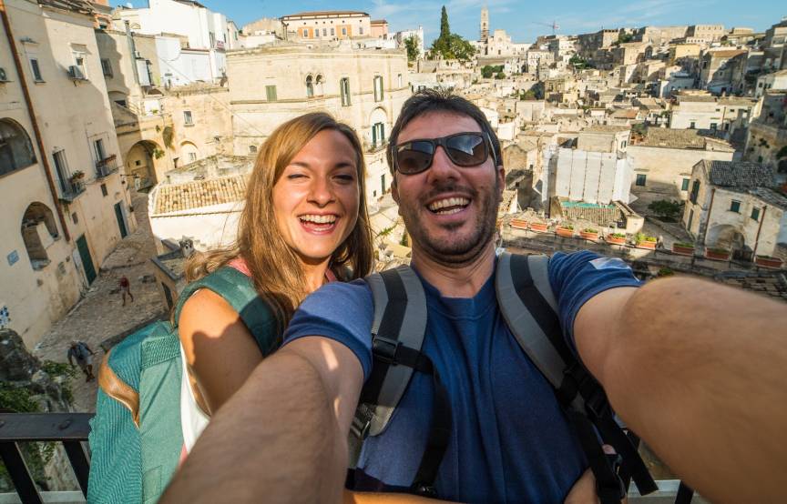 Pärchen macht ein Selfie während einer Rundreise durch Süditalien, im Hintergrund Matera