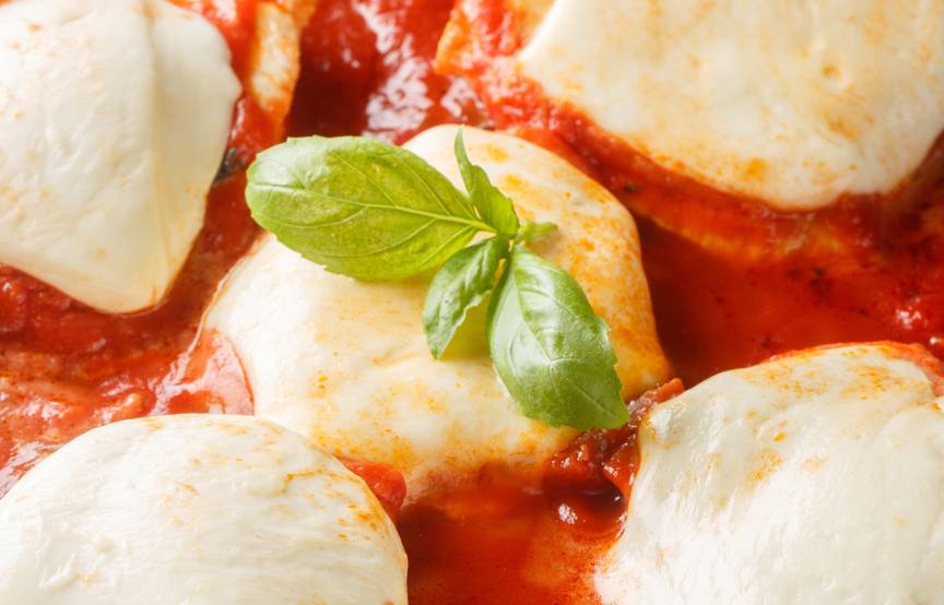 Überbackenes Tomate-Mozzarella-Hähnchen alla Pizzaiola in einer Pfanne garniert mit frischem Basilikum