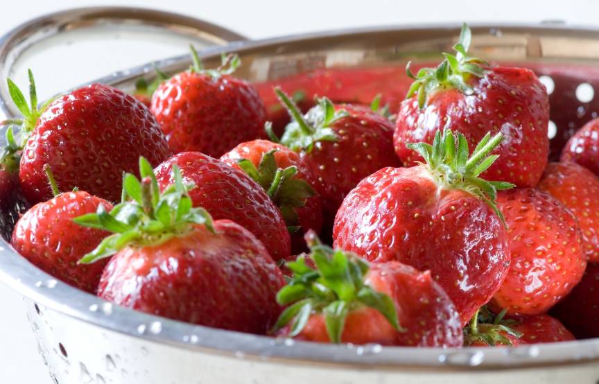 Ganze, nasse Erdbeeren mit Grün in einem silbernen Lochsieb