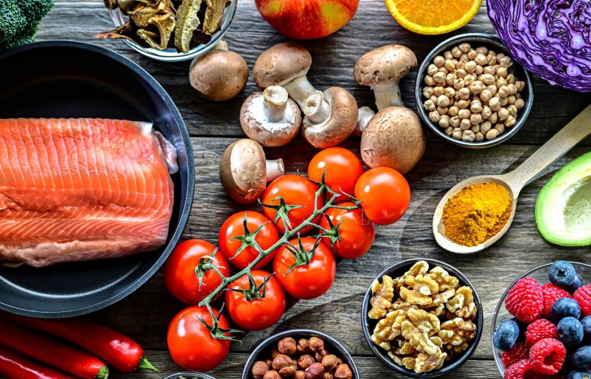 Verschiedene antientzündlich wirkende Lebensmittel auf einem Holztisch verteilt von oben