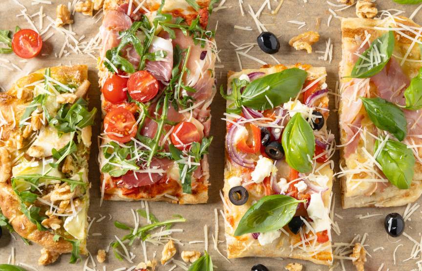 Vier verschieden belegte, angeschnittene Pinsen auf einem Tisch von oben