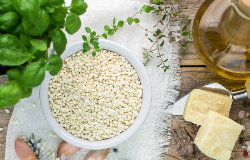 Risottoreis und weitere Risottozutaten auf einem Holztisch von oben