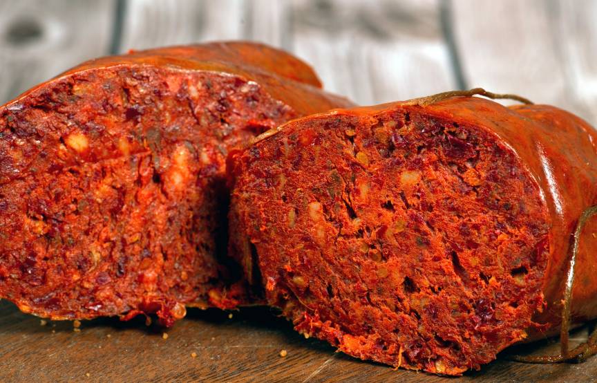 Eine Nduja-Salami halbiert auf einem Holzbrett
