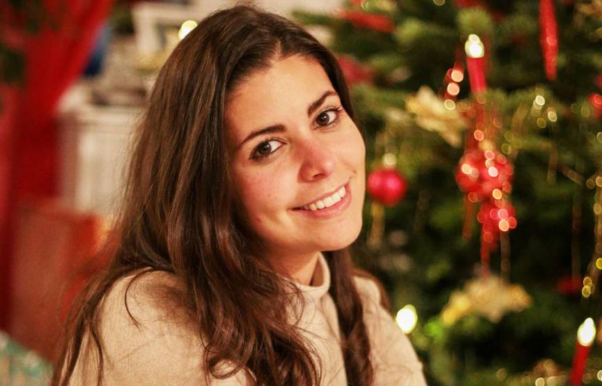Serena Loddo vor einem geschmückten Weihnachtsbaum umgeben von Geschenken