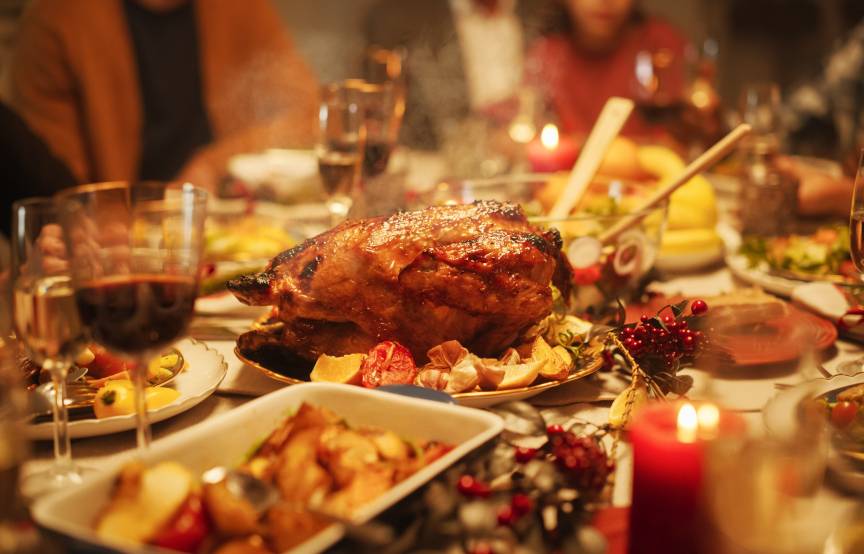 Eine gedeckte Festtafel mit Fleisch und vielen Beilagen, an dem mehrere Menschen sitzen