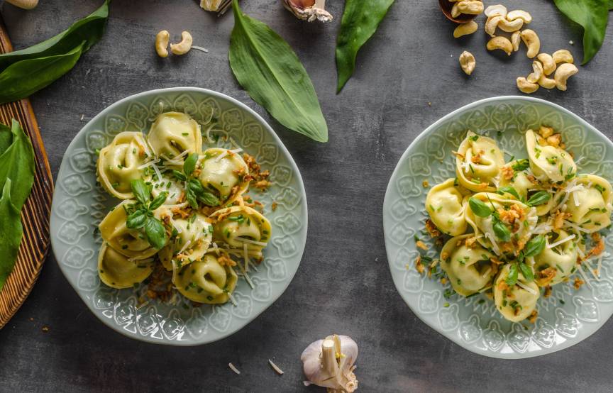 Selbstgemachte Tortellini mit verschiedenen Zutaten für Füllungen daneben auf einem Tisch