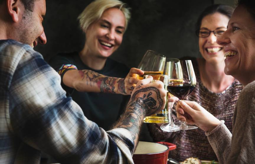 Vier Menschen sitzen bei einem italienischen Abendessen und stoßen mit unterschiedlichen Weinen an