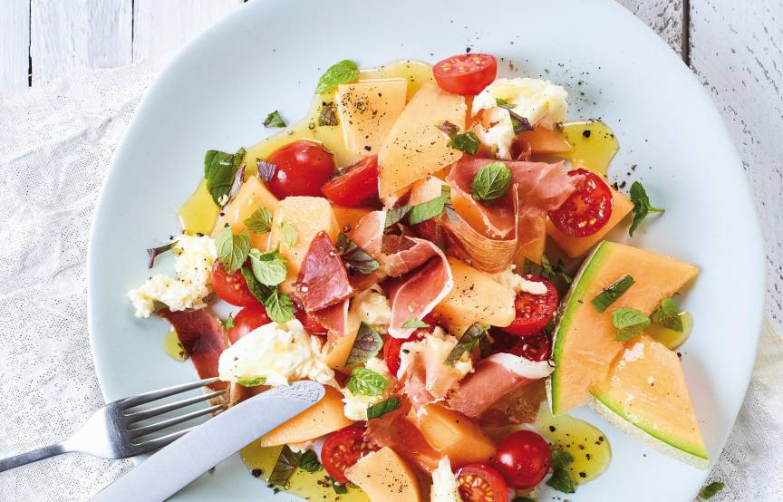 Melone-Mozzarella-Salat mit Schinken angerichtet auf einem Vorspeisenteller