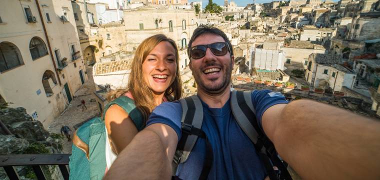 Pärchen macht ein Selfie während einer Rundreise durch Süditalien, im Hintergrund Matera