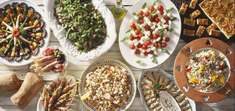 Italienisches Buffet aus Antipasti, Hauptgerichten und Desserts auf einem weißen Holztisch Italienisches Buffet aus Antipasti, Hauptgerichten und Desserts auf einem weißen Holztisch