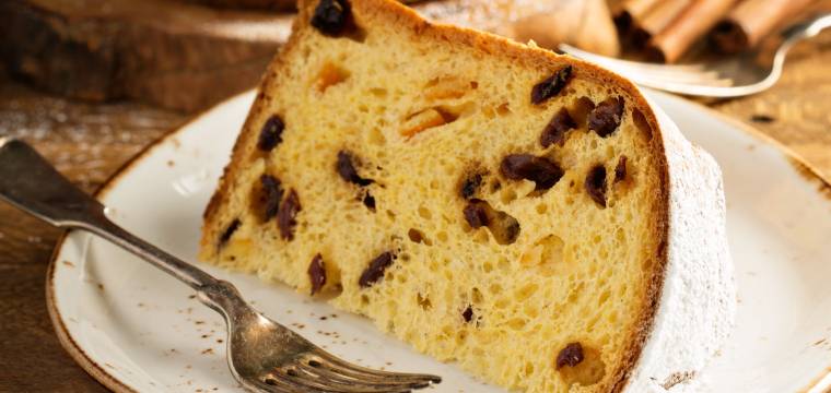 Panettone angeschnitten auf einem Teller, davor ein Stück in Nahaufnahme