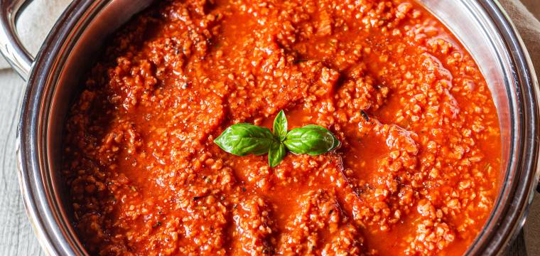 Bolognese Soße in einem Topf garniert mit frischem Basilikum auf einem Küchentisch