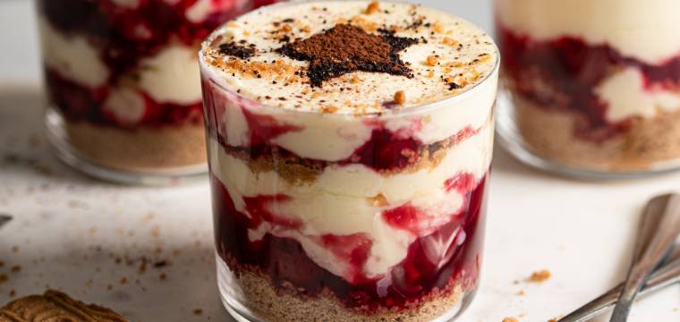 Weihnachtstiramisu in drei Gläser gefüllt, daneben Spekulatius und Zimt auf einem Tisch