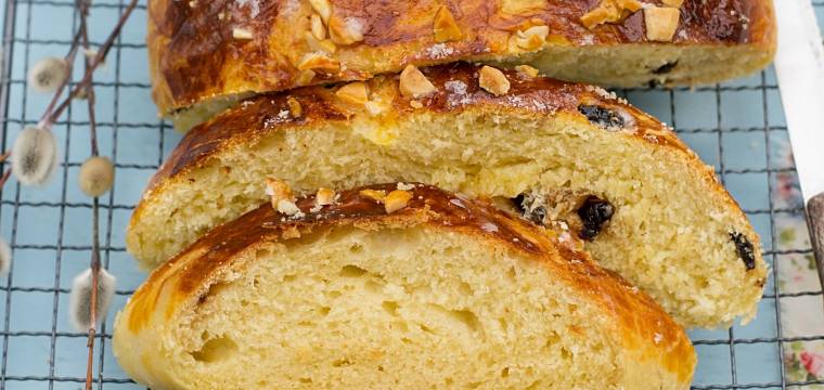 Osterbrot mit Rosinen und Mandeln bestreut angeschnitten auf einem Kuchengitter