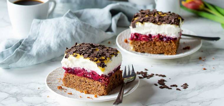 Zwei Stücke Oster-Blechkuchen mit Sahne, Kirschkompott und Eierlikör-Topping auf Kuchentellern Zwei Stücke Oster-Blechkuchen mit Sahne, Kirschkompott und Eierlikör-Topping auf Kuchentellern