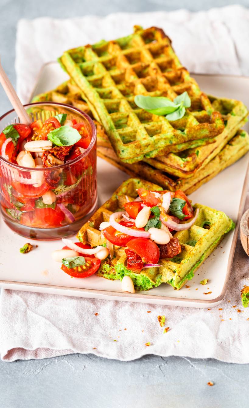 Drei rechteckige Parmesan-Bärlauchwaffeln angerichtet mit Tomatensalat auf einer Servierplatte