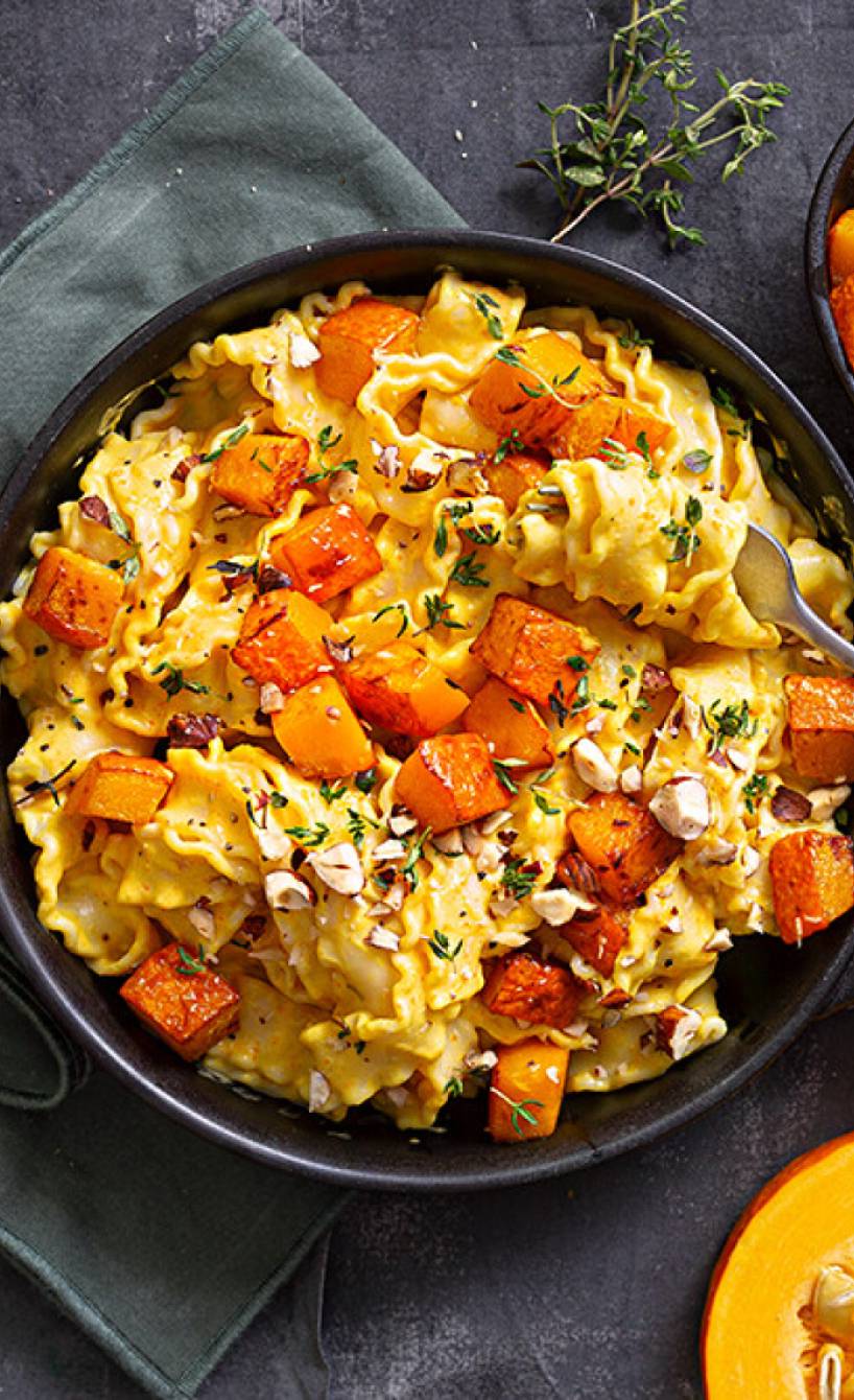 Mafaldine Bandnudeln in einer Pfanne mit Kürbiswürfeln getoppt