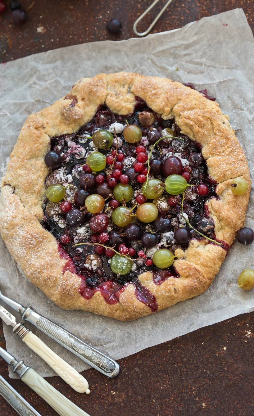 Beeren-Crostata mit verschiedenen Beeren und Ricotta gefüllt auf einem Stück Backpapier von oben