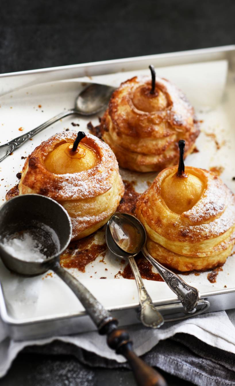 Drei gefüllte Bratbirne im Blätterteigmantel auf einer Servierplatte bestäubt mit Puderzucker