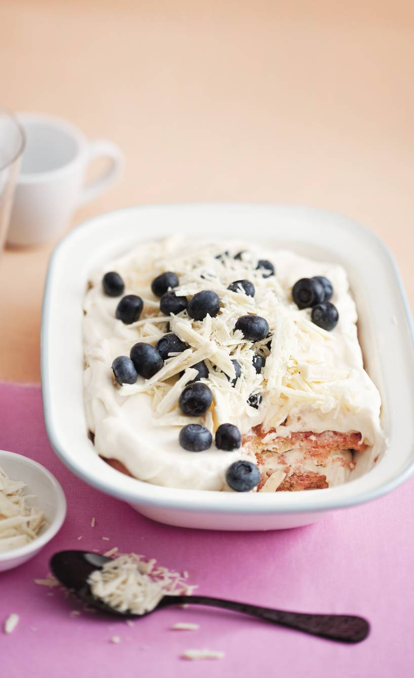 Helles Tiramisu in einer Schale mit Blaubeeren und weißen Schokoladenraspeln getoppt