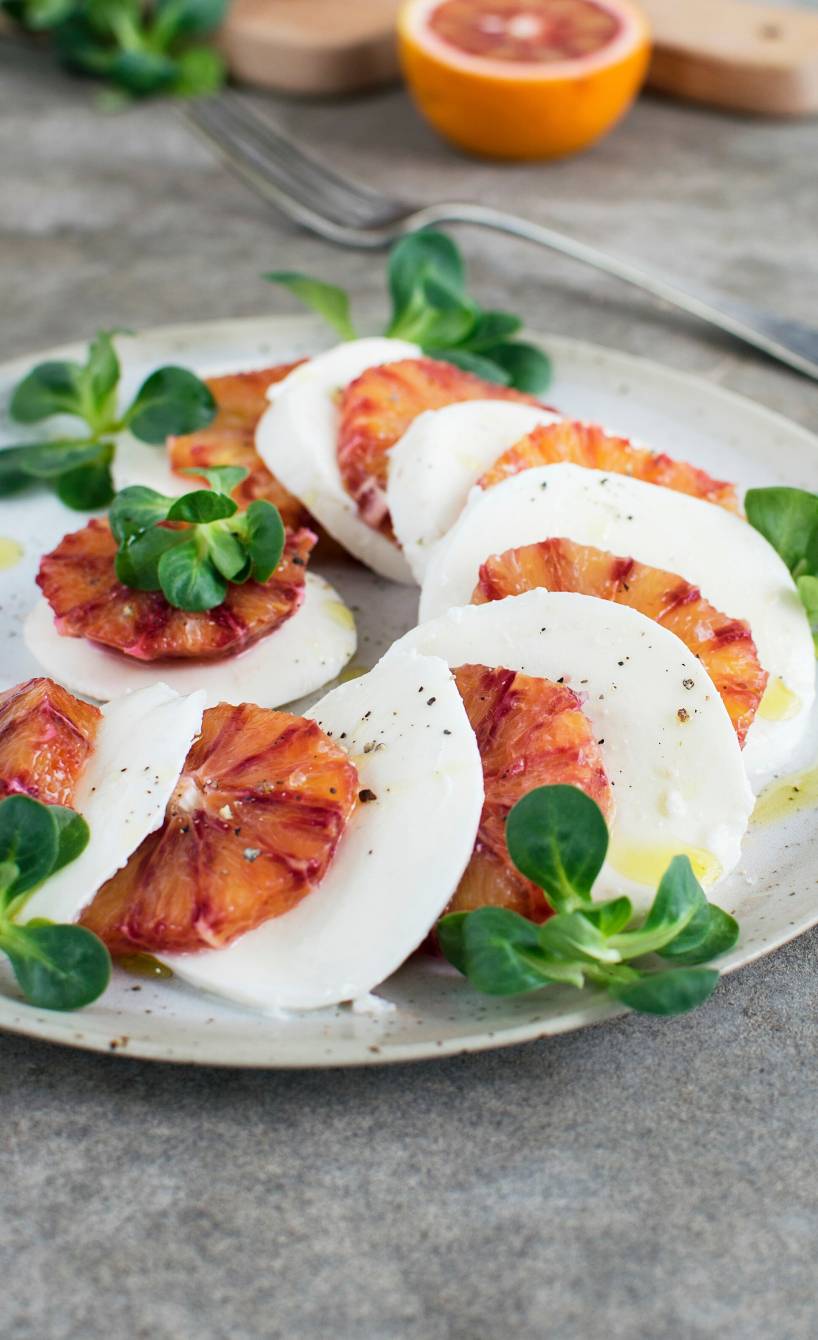 Blutorangen-Caprese gefächert auf einem Vorspeisenteller garniert mit Feldsalat