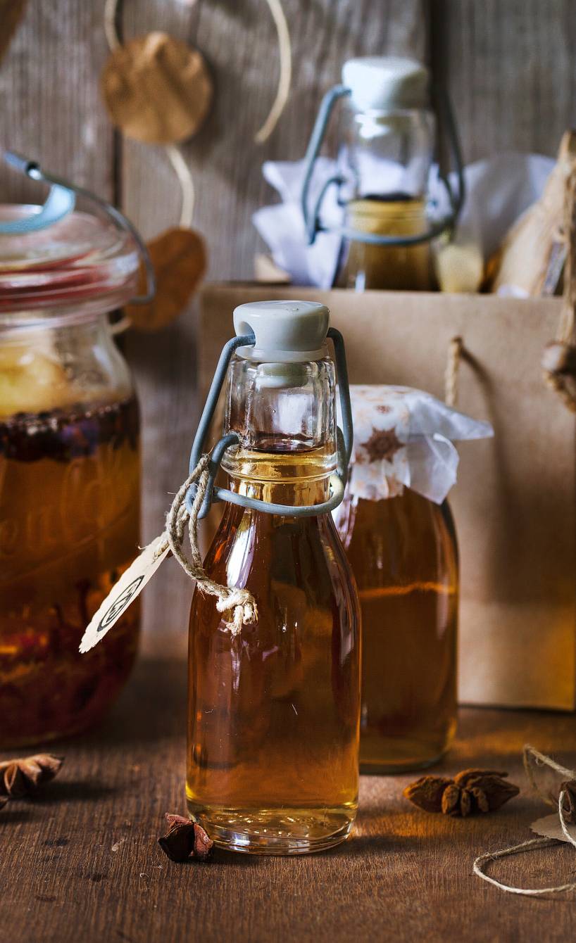Bratapfellikör in mehrere Flaschen gefüllt, daneben eine weihnachtliche Geschenktüte