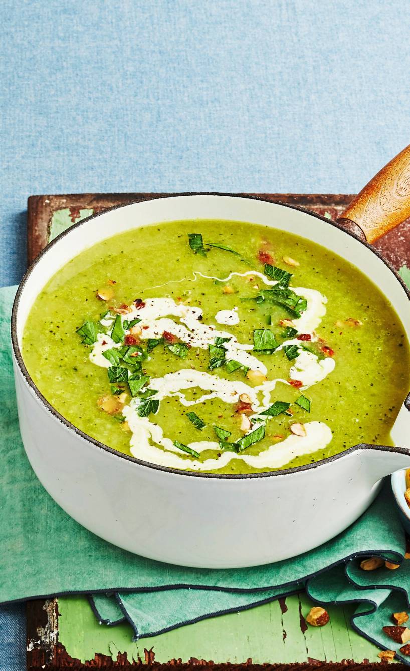 Kartoffel-Brokkolisuppe mit Crème fraîche- und Rauchmandel-Topping in einem Stieltopf auf einem Tisch