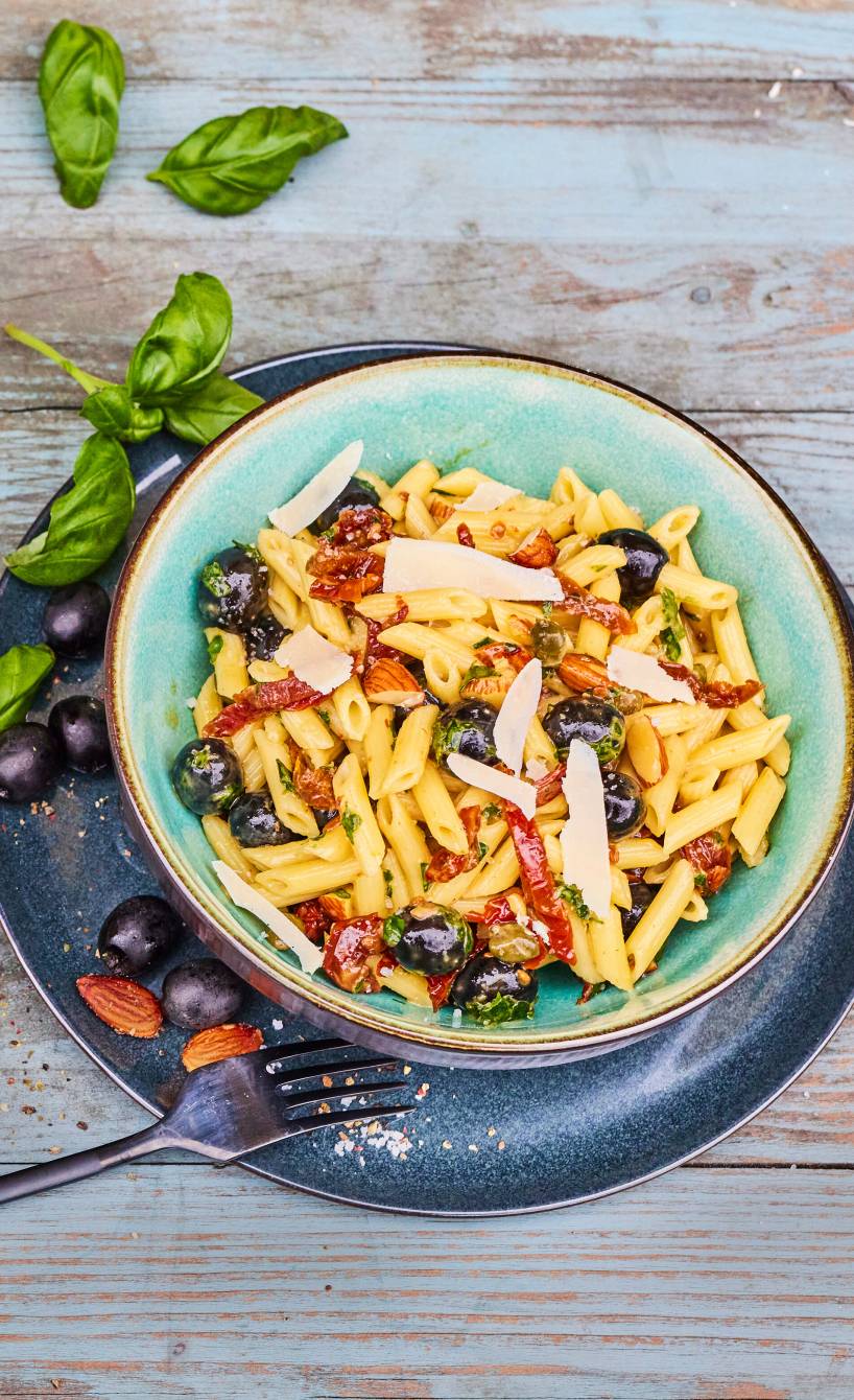 Italienischer Nudelsalat mit Parmesan und Mandeln getoppt in einer Schüssel auf einem Tisch
