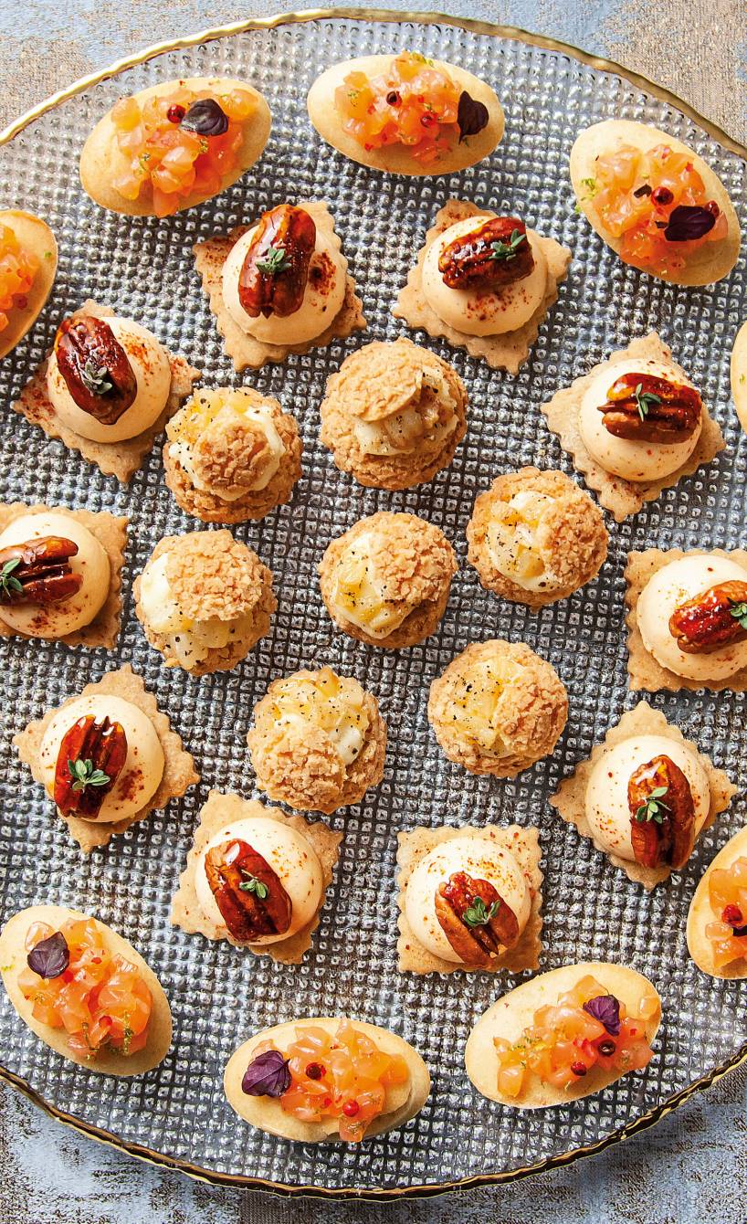 Parmesancracker auf einer runden Platte getoppt mit Kürbiscreme und Pekannüssen