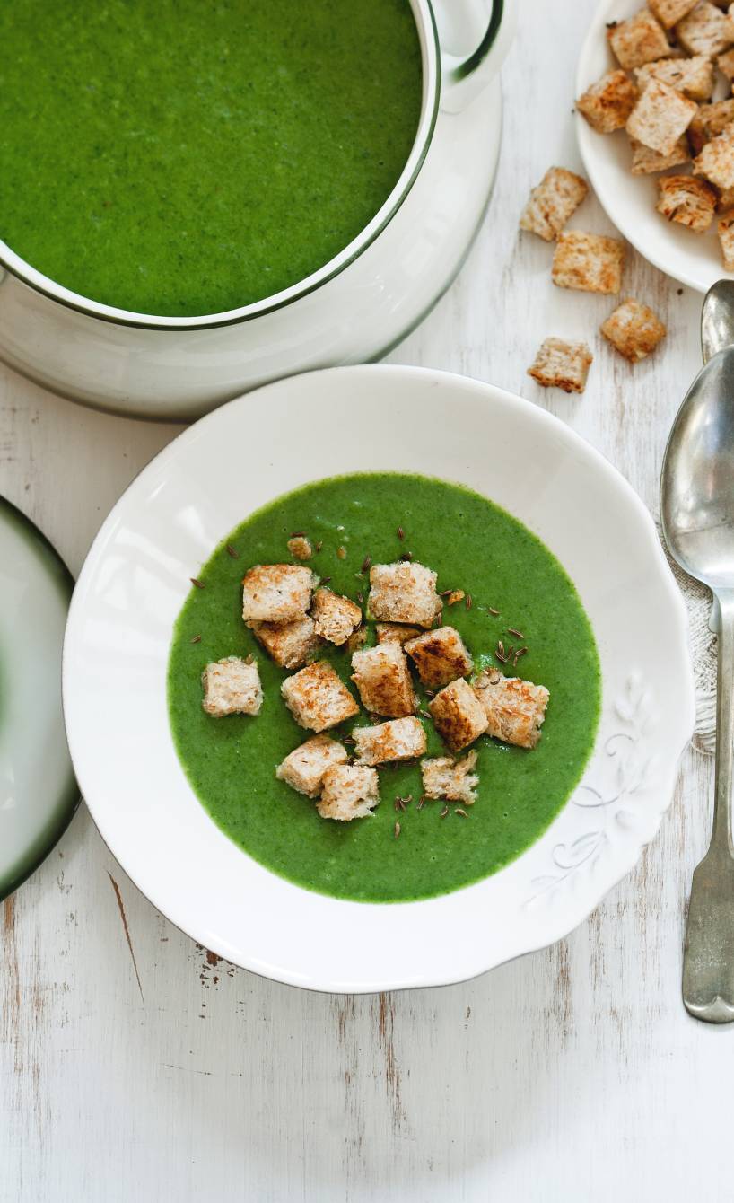 Kartoffel-Spinatsuppe angerichtet auf einem Suppenteller getoppt von selbstgemachten Vollkorn-Croûtons