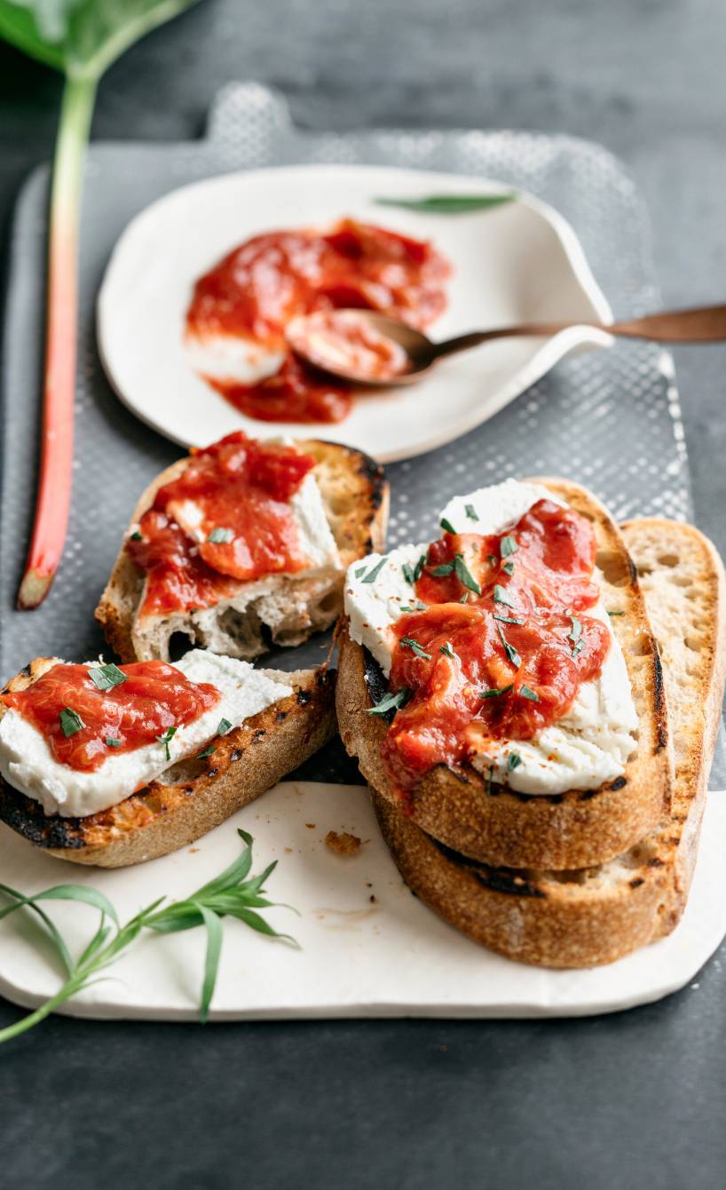 Vier knusprige Crostini mit Ziegenfrischkäse und Rhabarber-Tomaten-Chutney auf einem Vorspeisenteller