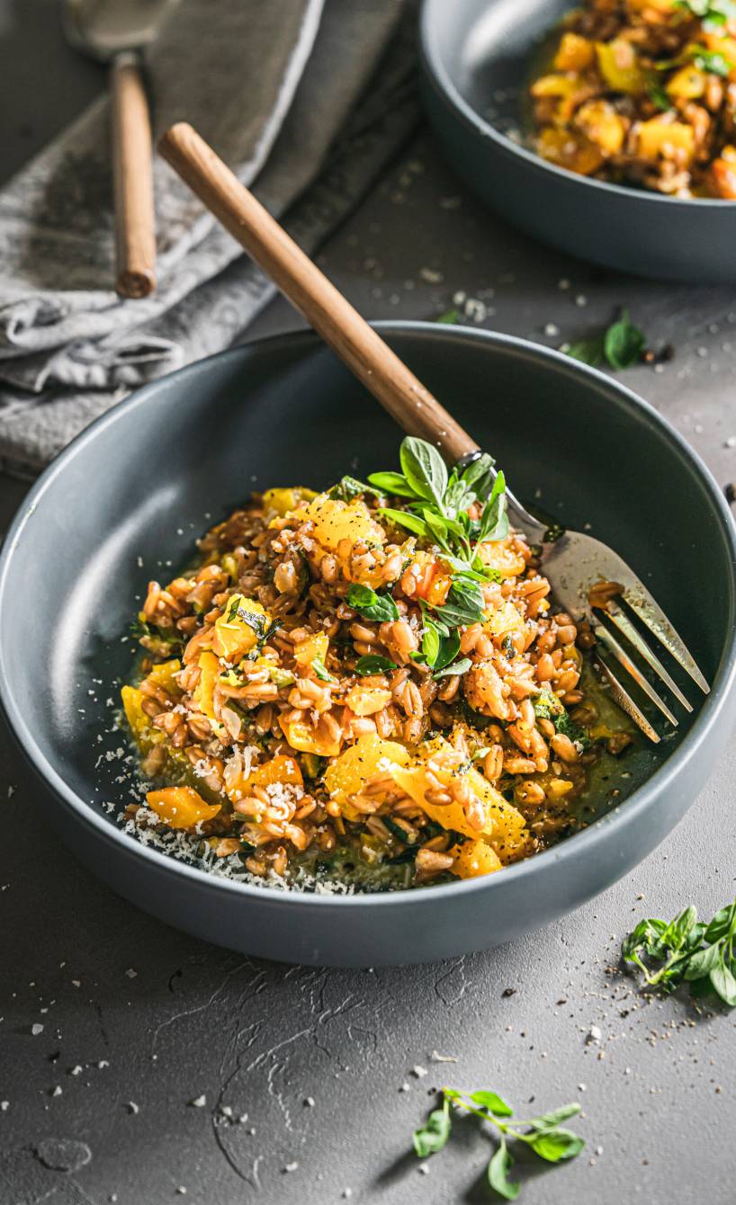 Dinkel-Risotto mit Kürbis und gelber Paprika getoppt von Parmesan in einer Schüssel