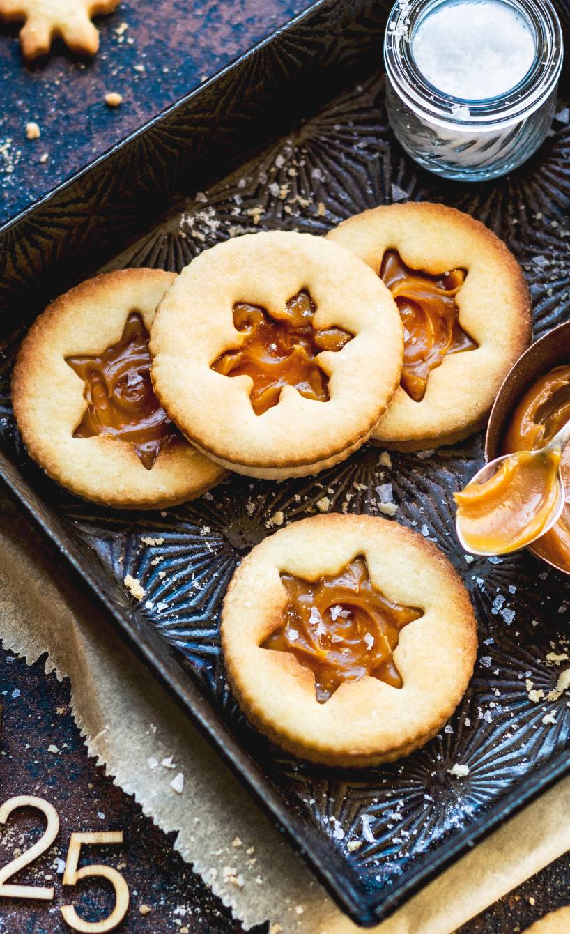 Runde Doppeldecker-Plätzchen mit Sternausschnitt und Karamellfüllung auf einem Kuchenteller