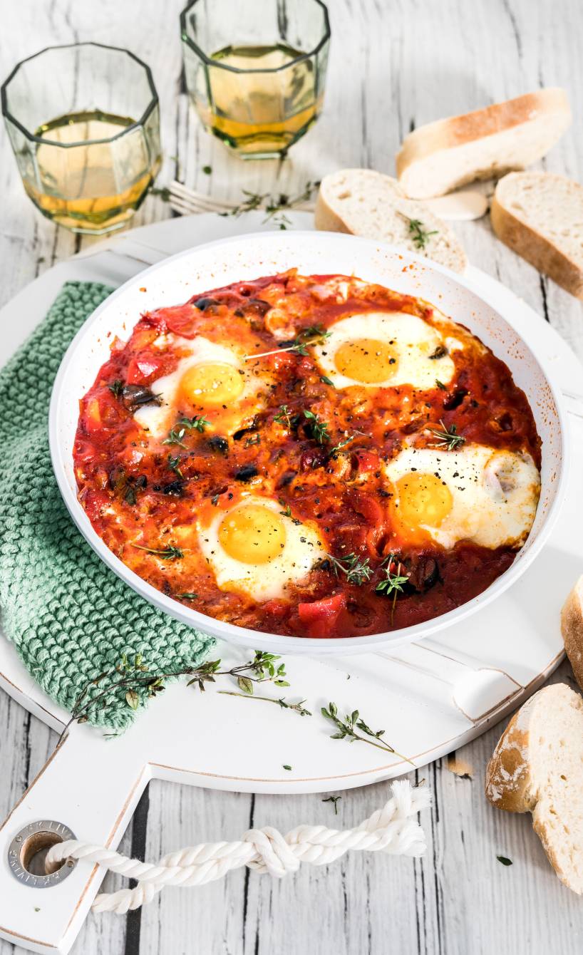 Eier in Tomatensauce all'arrabbiata in einer Pfanne, daneben Ciabattascheiben