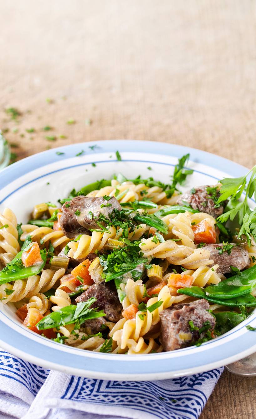 Fusilli mit Entenbrust-Ragout auf einem tiefen Teller garniert mit frischen Kräutern