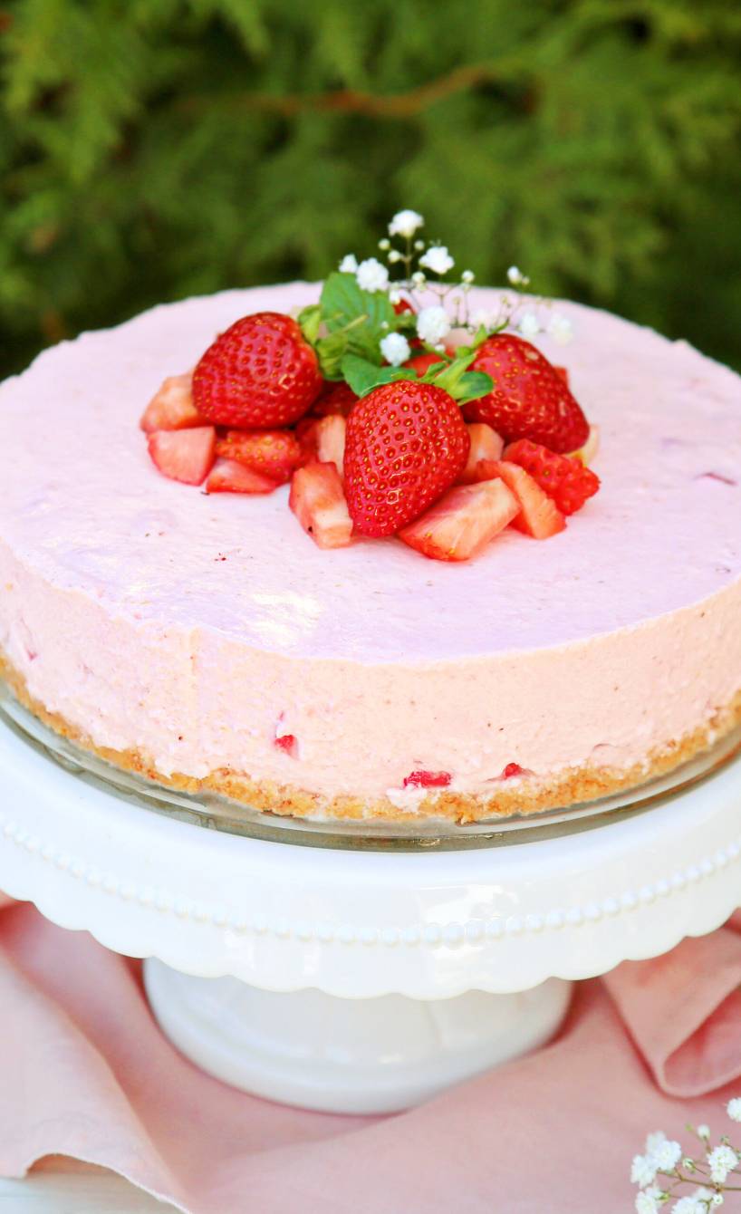 Erdbeer-Joghurt-Torte dekoriert mit frischen Erdbeeren auf einer Tortenplatte im Garten