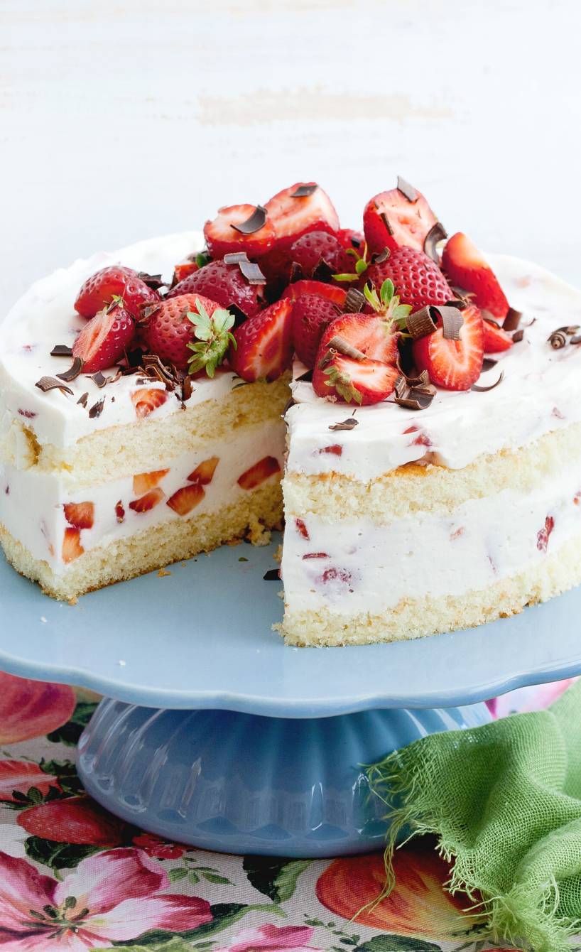 Zweistöckige Erdbeer-Joghurt-Torte mit Biskuit angeschnitten auf einer Tortenplatte